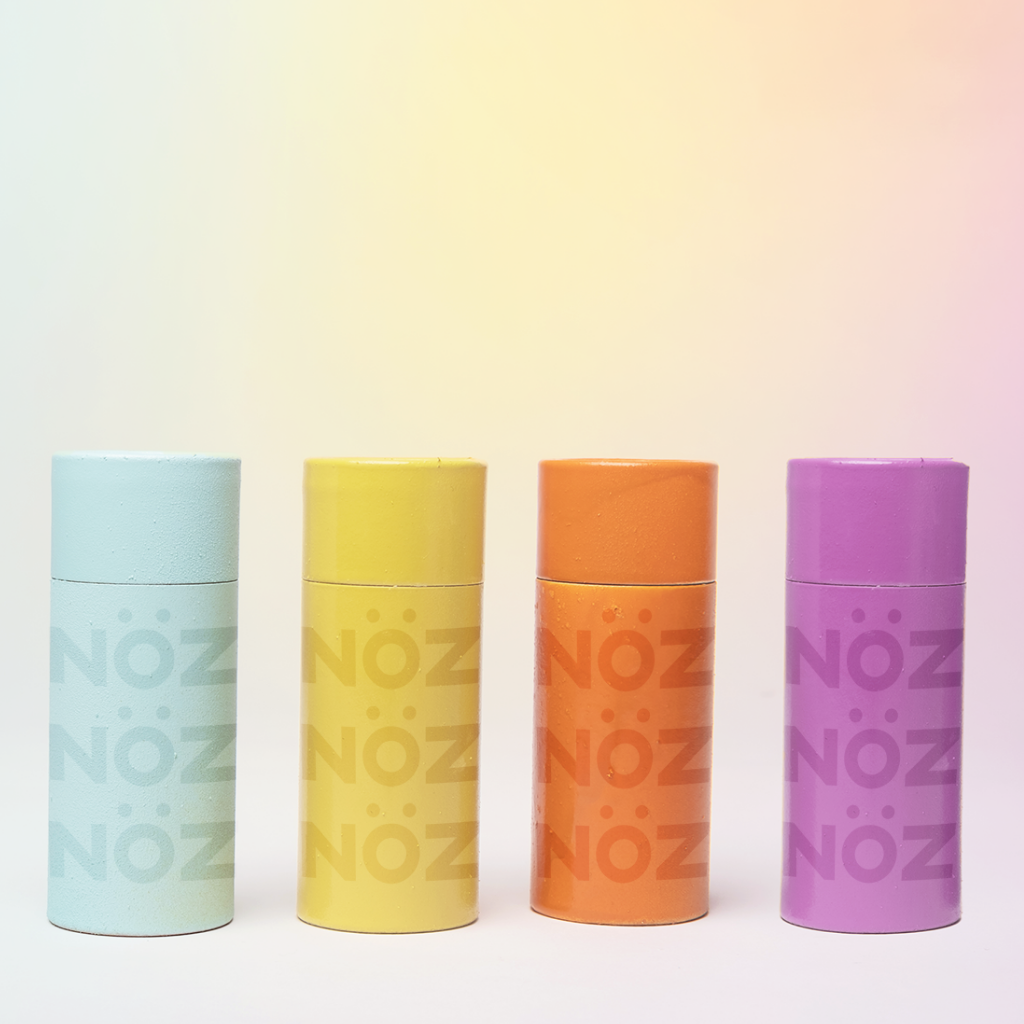 Nöz’s natural zinc and vegan sunscreen sticks lined up in row in all 4 colors, with their lids on.