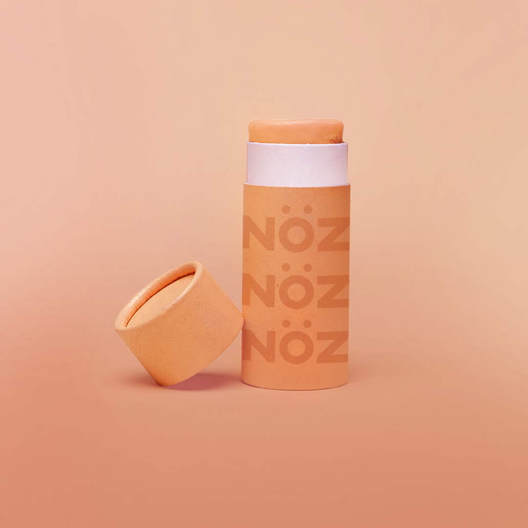 Nöz’s natural zinc and vegan sunscreen stick in neon orange, with its cap off.