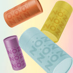 Load image into Gallery viewer, Nöz’s natural zinc and vegan sunscreen sticks levitating on a colorful background in all 4 colors, with their lids on.
