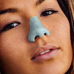 Girl with brown hair and eyes wearing Nöz’s reef safe and vegan sunscreen in neon blue on nose.